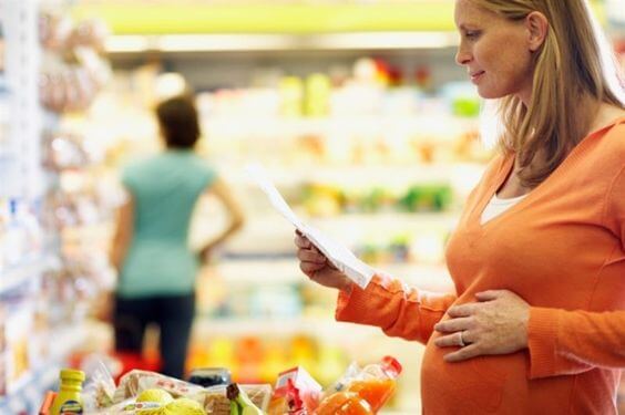 Femme enceinte avec une liste de courses au supermarché