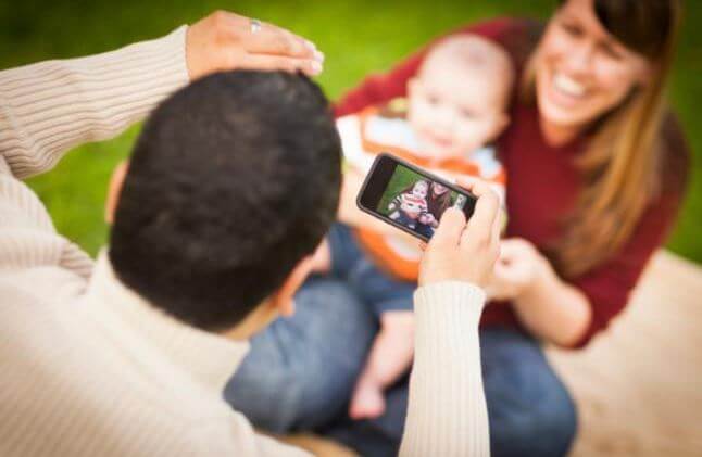 Père prenant une photo de son bébé avec le flash de l'appareil ce qui peut faire les bébés devenir aveugles