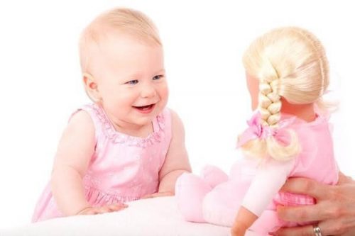 Une petite fille rie face à une poupée