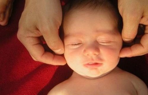 Bébé caressé à la tête par son père pour calmer le réflexe de Moro