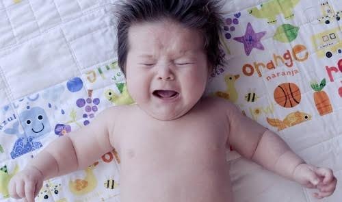 Bébé couché en pleurs et qui sursaute