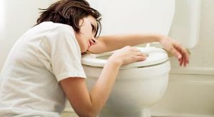 Femme au-dessus des toilettes souffrant de nausées durant la grossesse