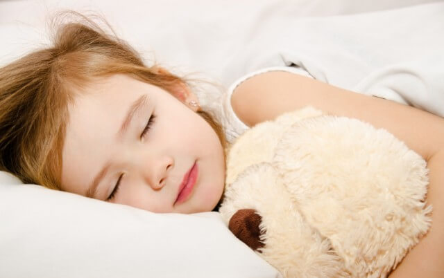 Petite fille endormie avec une peluche 