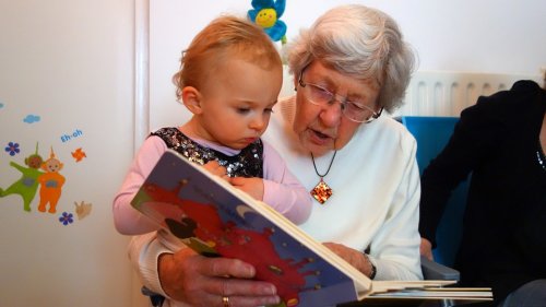Grand-mère en train de lire une histoire à une petite fille dans ses bras 