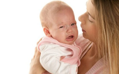 Bébé qui pleure dans les bras de sa maman