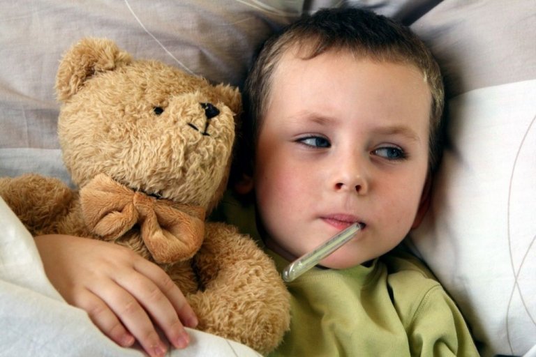 Enfant couché avec une peluche et un thermomètre dans la bouche 