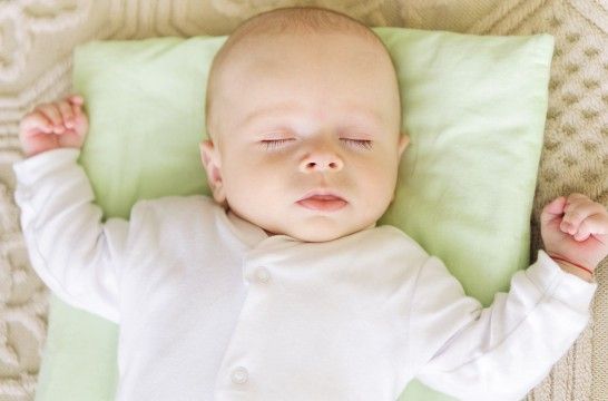 Un nouveau-né endormi sur le dos sur un coussin bien que les oreillers pour les bébés soient à éviter