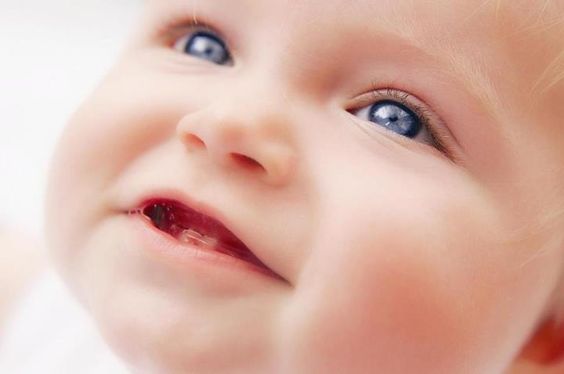 Bébé aux yeux bleus avec ses premières dents
