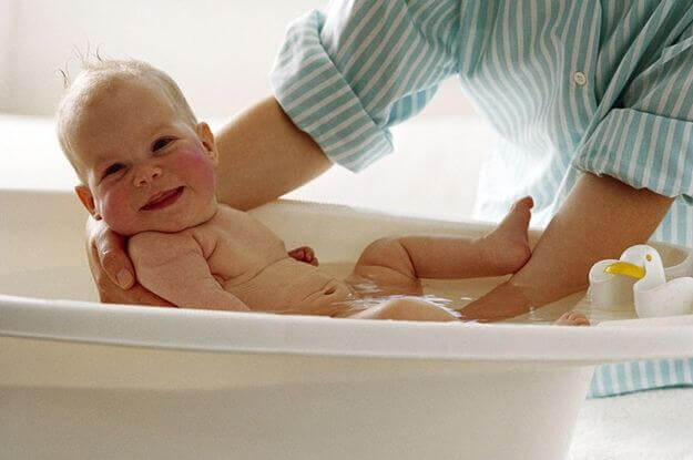 Un bébé souriant qui prend son bain 