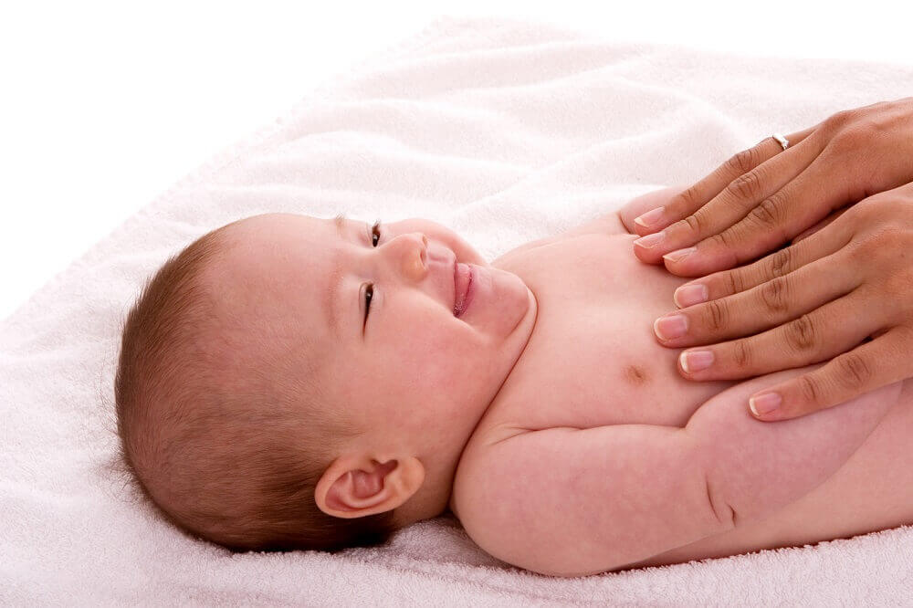 Bébé souriant massé par les mains d'une adulte, un exercice de relaxation pour les enfants