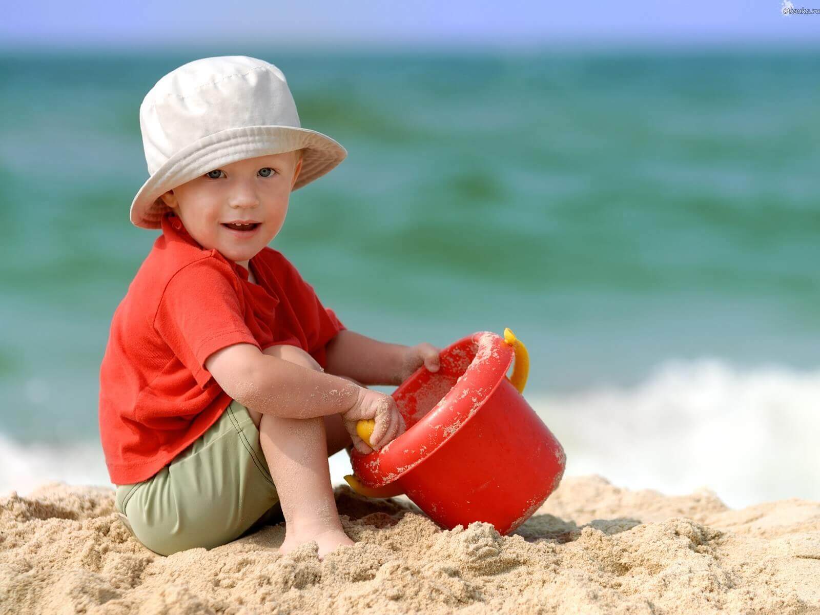 Enfant à la plage dans le sable, en plein jeu créatif avec un seau