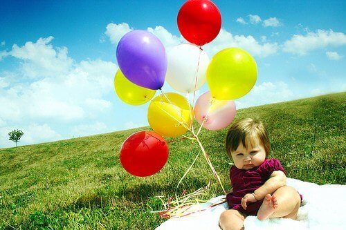 Un bébé sur une pelouse avec des ballons de baudruche