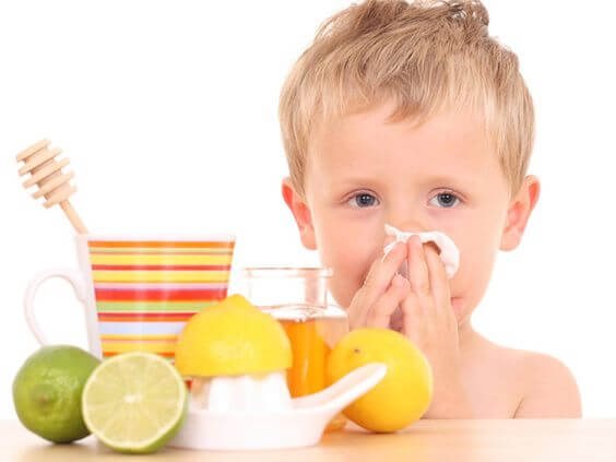 Petit garçon qui se mouche avec un thé au miel et au citron qui contribue à renforcer les défenses immunitaires des enfants