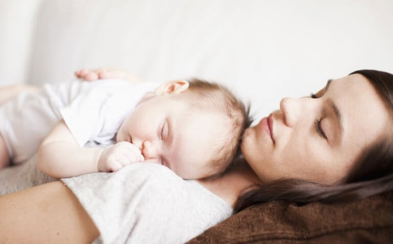 Bébé endormi dans les bras de sa maman