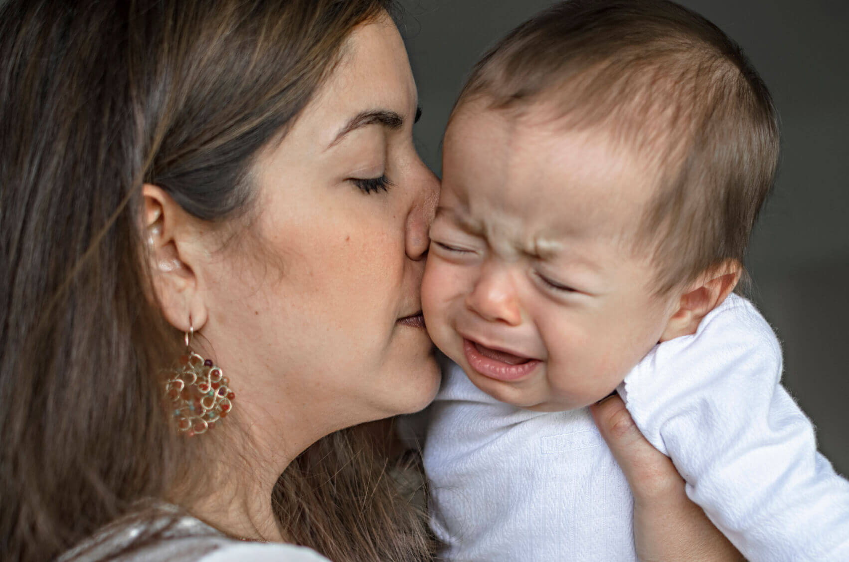 Un bébé en pleurs embrassé par sa maman