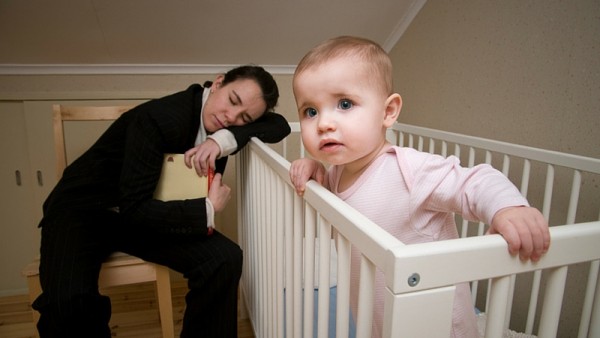 Maman endormie avec un livre sur le berceau de son bébé éveillé