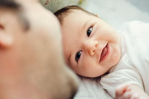 Bébé souriant face à son père, dont le rôle est important pour les enfants 