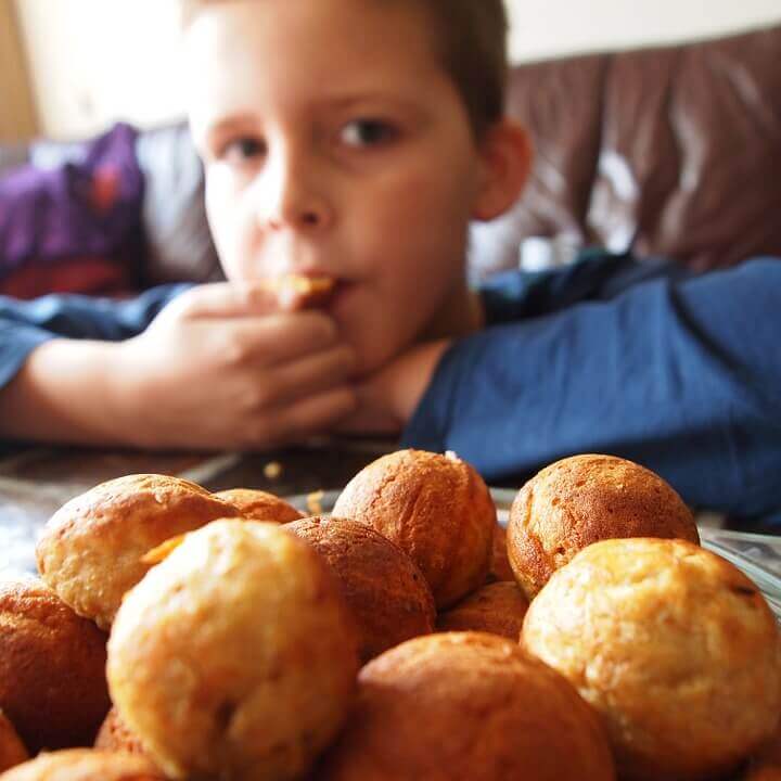 Un petit garçon mange des beignets