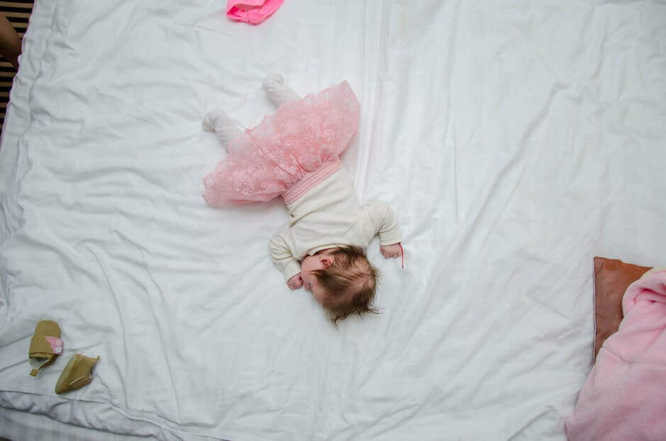 Une petit fille endormie dans un grand lit 