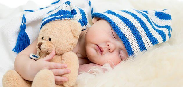 Bébé endormi avec une peluche et un bonnet sur la tête