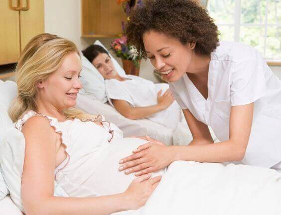 Infirmière avec les mains sur le ventre d'une femme enceinte 
