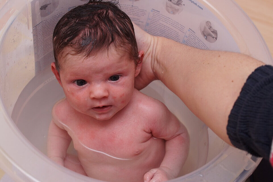 Un bébé prenant son bain dans une bassine