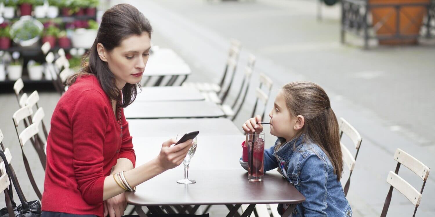Une mère sur son smartphone au restaurant avec sa fille