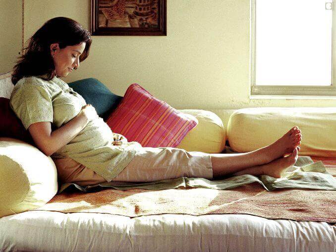 Femme enceinte allongée regardant son ventre