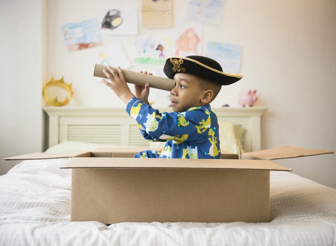 Un petit garçon qui n'a pas besoin de cadeaux et qui joue au pirate avec une boite et un tube en carton 