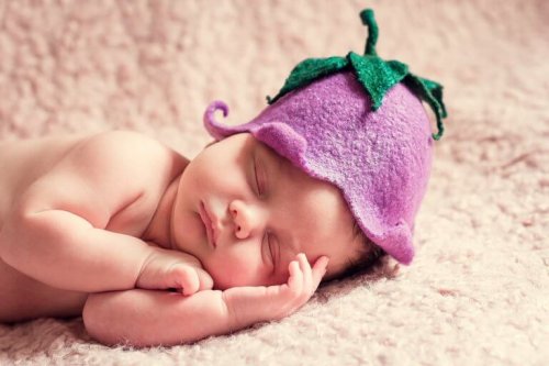 Un bébé endormi avec un bonnet de fruits sur la tête 