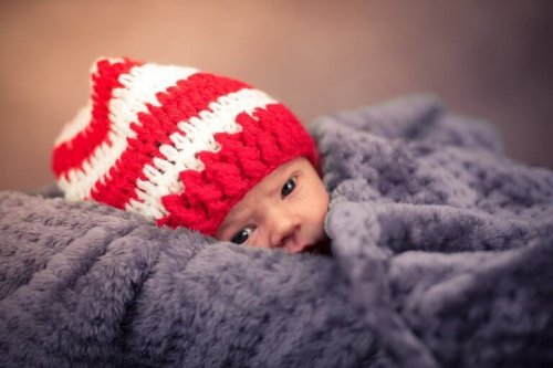Un bébé enveloppé d'une grosse couverture avec un bonnet 