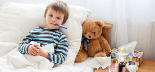 Un petit garçon malade au lit avec un thermomètre dans la bouche 