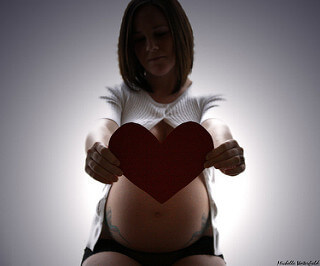 Une femme enceinte avec un cœur en carton