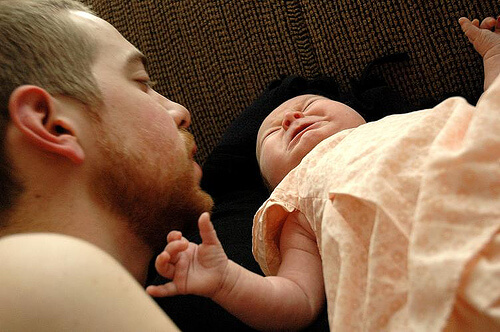 Un papa parle doucement à son bébé, une solution pour calmer les pleurs de votre bébé