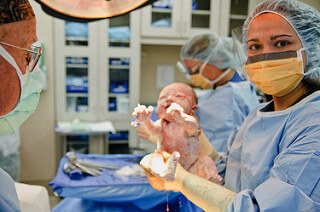 Un nouveau-né dans les mains d'une infirmière, après avoir fait le choix entre césarienne et accouchement 