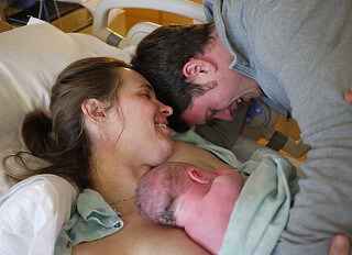 Une femme qui vient d'accoucher avec son bébé et son compagnon