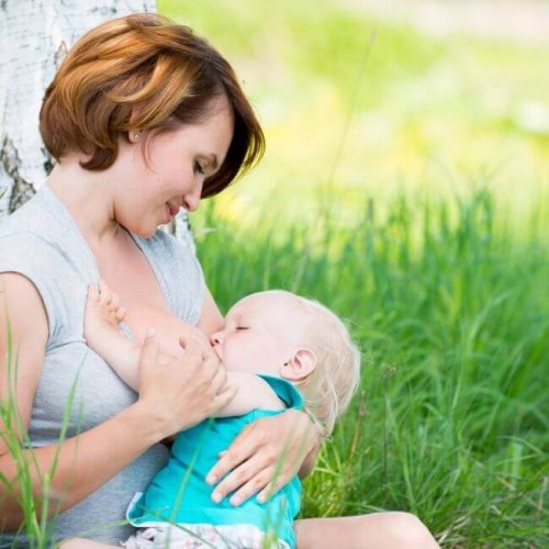 Une maman allaite son bébé dans un parc 