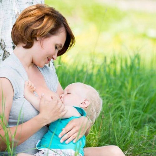 Une maman allaite son bébé dans un parc