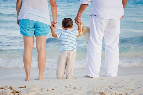 Un petit garçon tient les mains de sa maman et de son papa