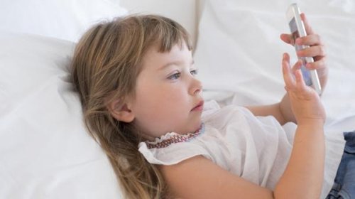 Une petite fille couchée avec un smartphone
