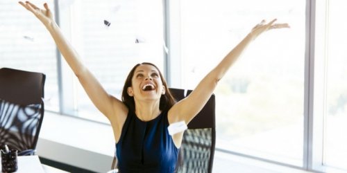 Une femme heureuse les bras en l'air dans son bureau