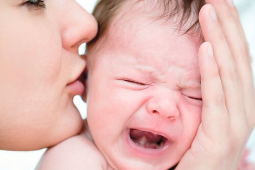 Un bébé en pleurs embrassé par sa maman