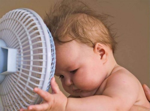 Un bébé devant un ventilateur. 