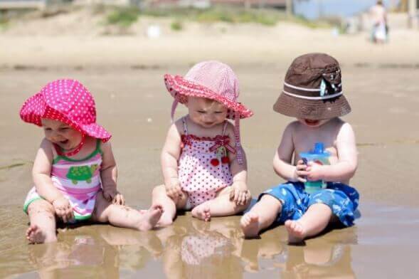 Trois jeunes enfants sur une plage. 