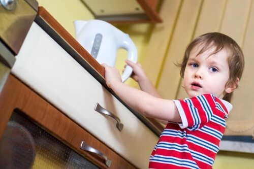 enfant tenant une theiere d' eau bouillante