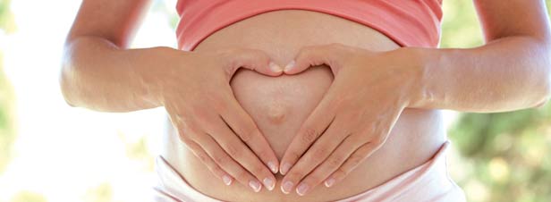 Une femme enceinte forme un coeur avec ses mains