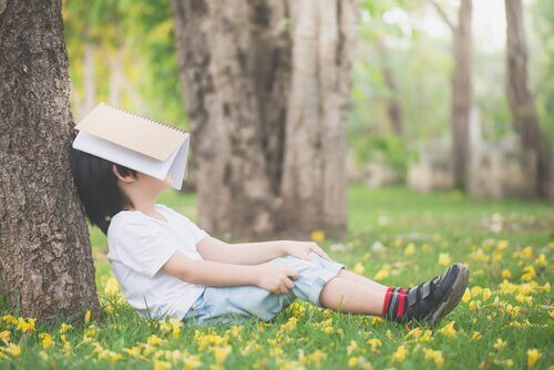 Un enfant se cache la figure avec un livre