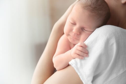 Un bébé dort dans les bras de sa mère