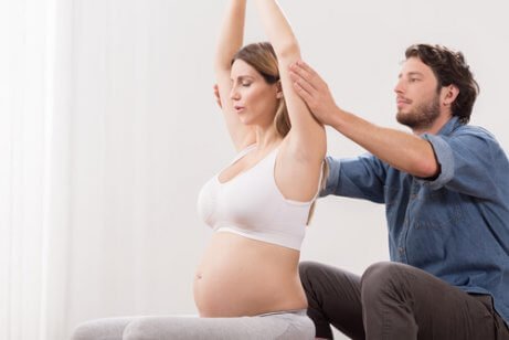 Un homme aidant sa femme à pratiquer des exercices pré-accouchement