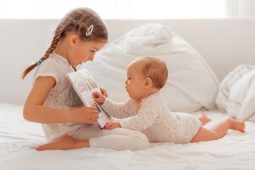 Un bébé écoute sa soeur lui lire une histoire